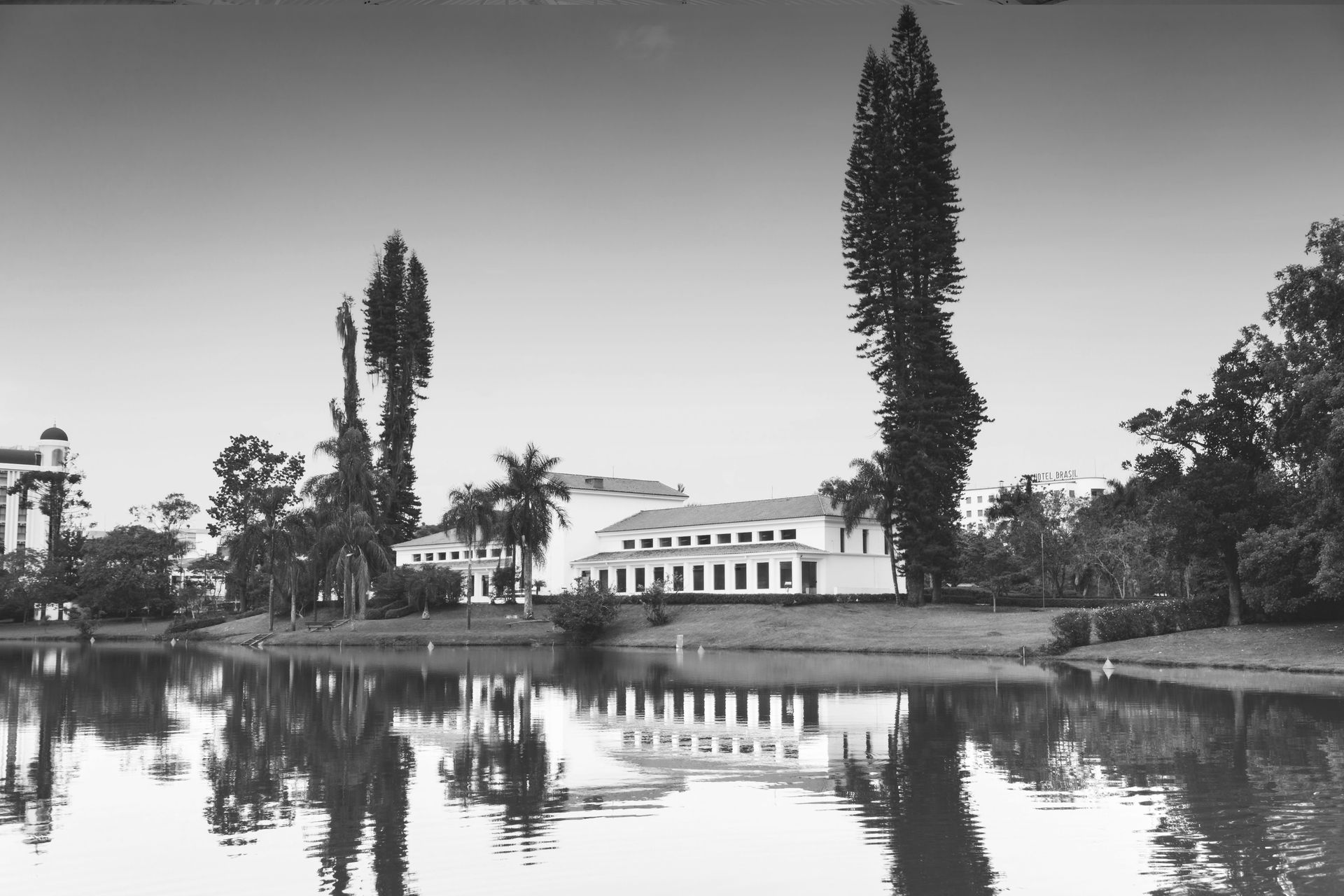 Uma foto em preto e branco de um lago com um prédio ao fundo