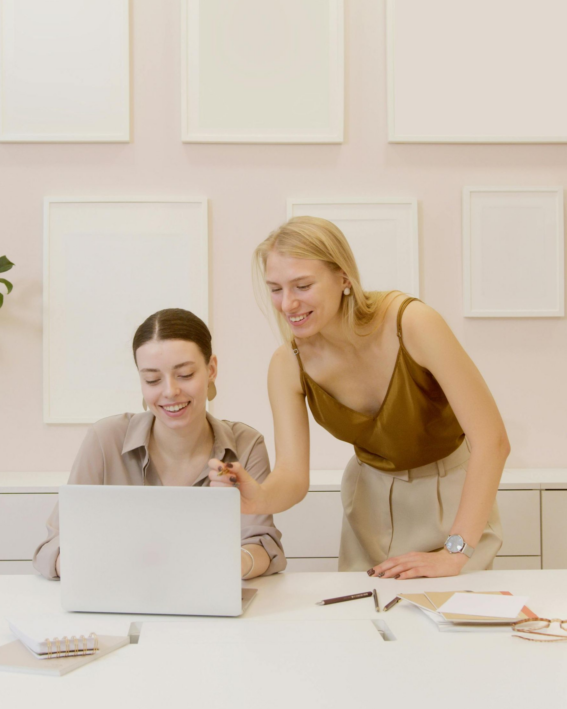 Students in a classroom. Some smiling and looking toward a person in front. Desks, window, bright lighting.
