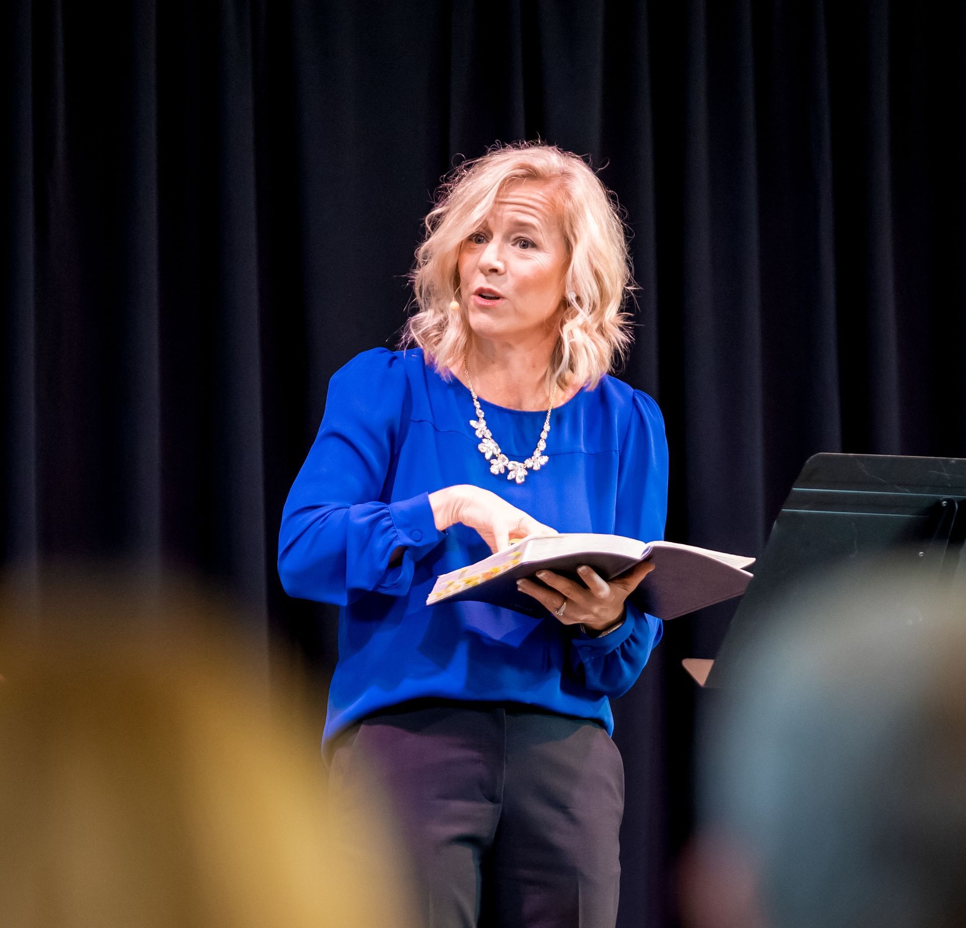 A woman in a blue shirt is reading a book