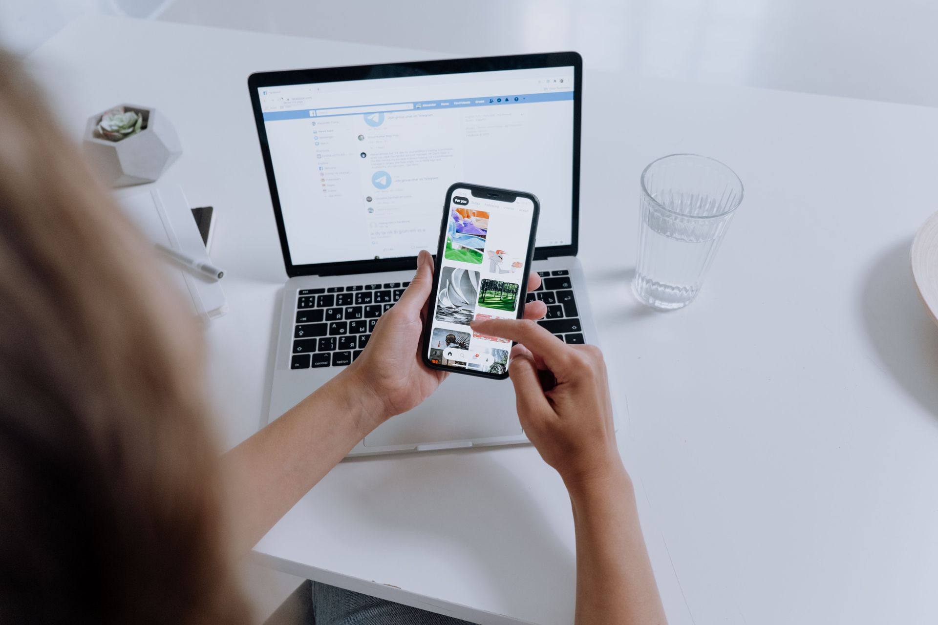 women working at a desk using a mobile phone and laptop for her business