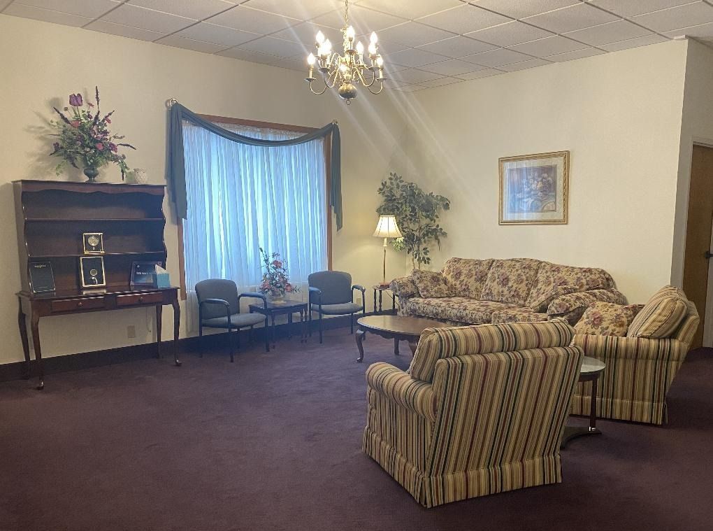 Quiet lounge with striped sofa, chairs, lamp, window, and dark carpet in a beige room
