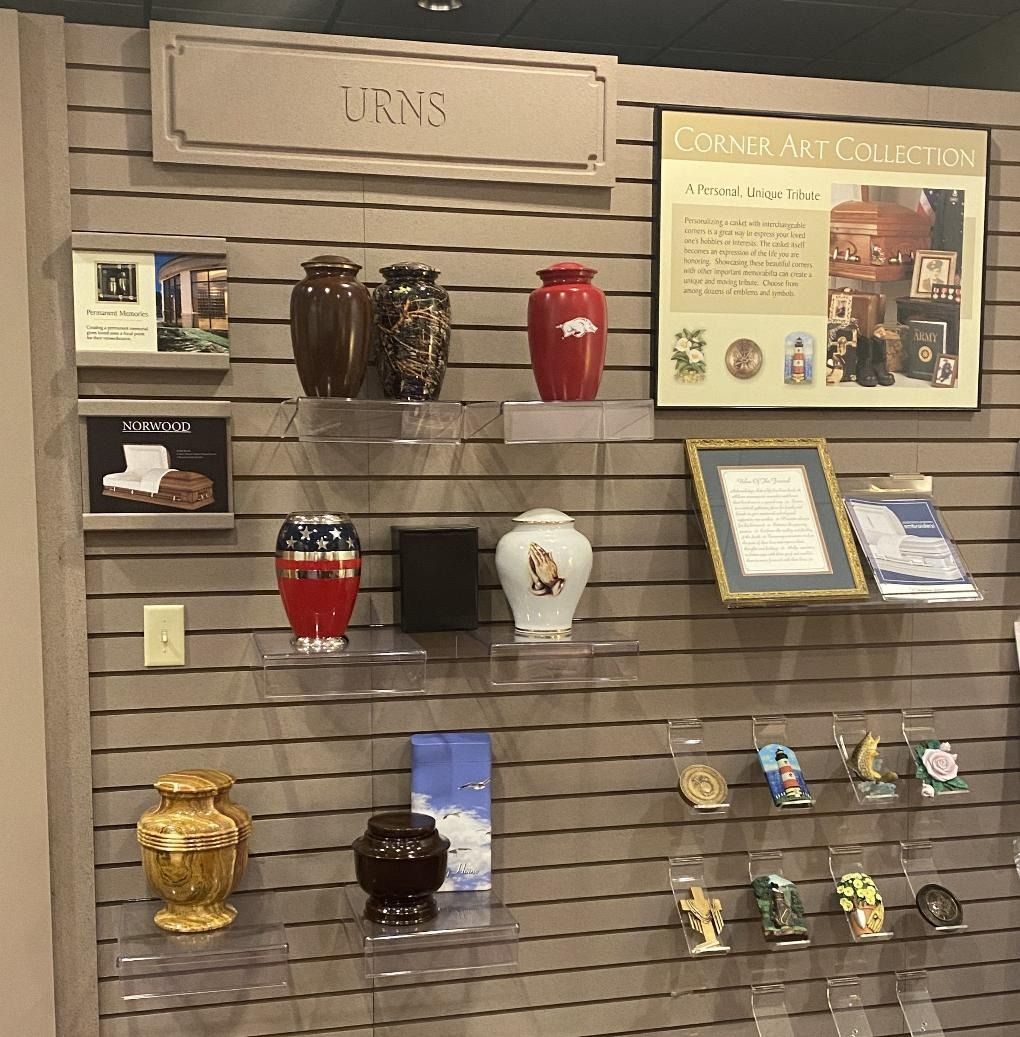 Display of decorative urns and small figurines on a slatwall shelf, with a sign and brochure to the right