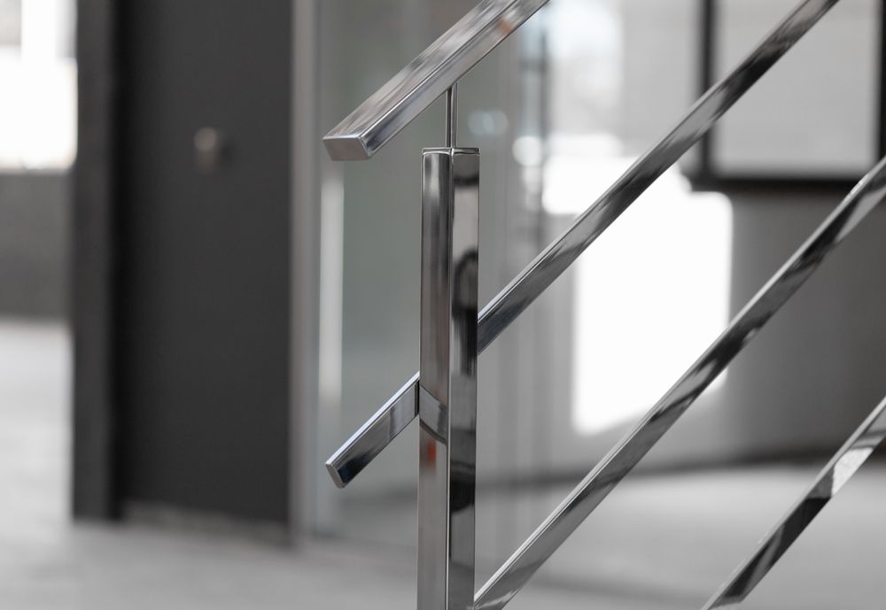 Close-up of a modern, polished stainless steel staircase railing with vertical and diagonal structural bars.