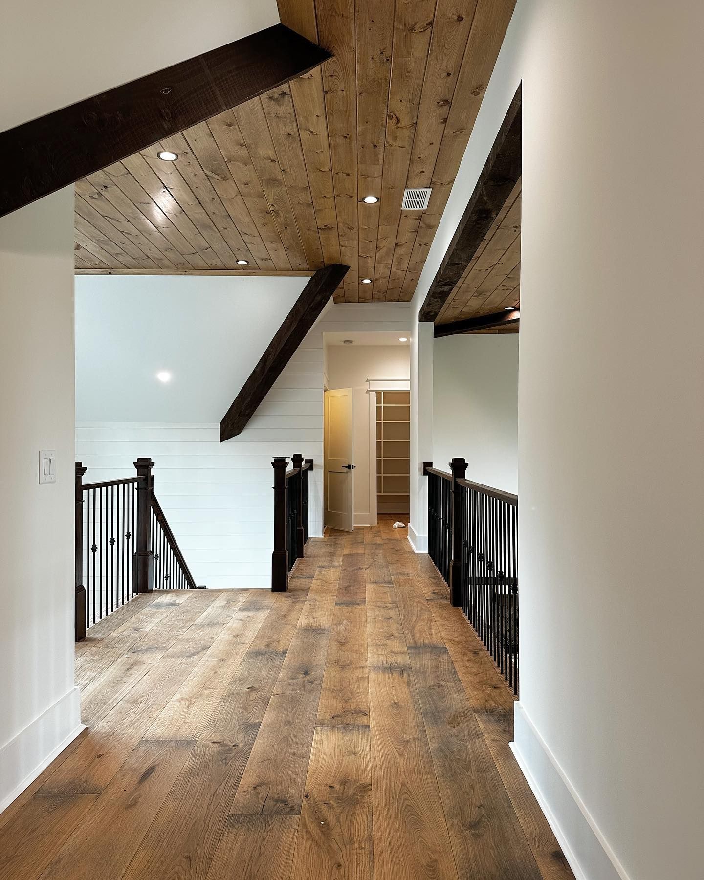 A hallway with wooden floors and white walls