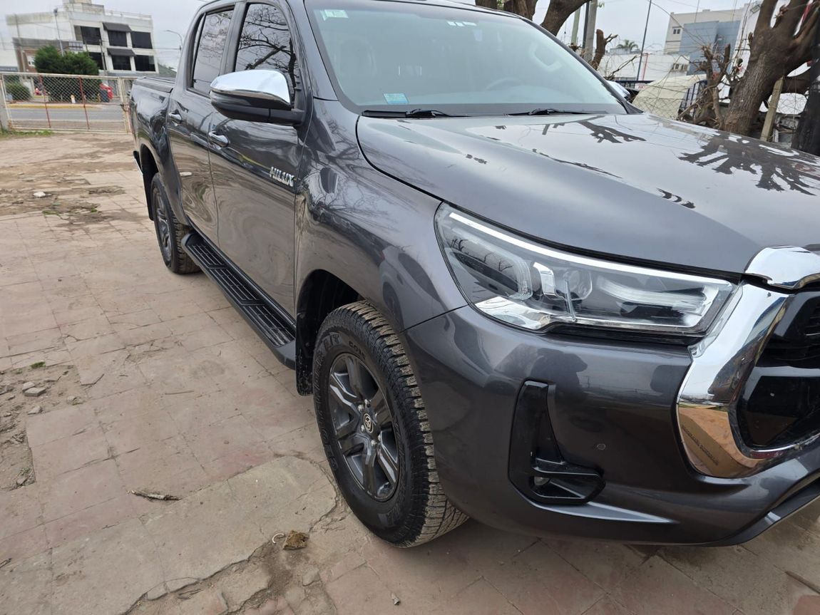 Un sedán plateado en un taller de reparación de automóviles, rodeado de herramientas y materiales de pintura.