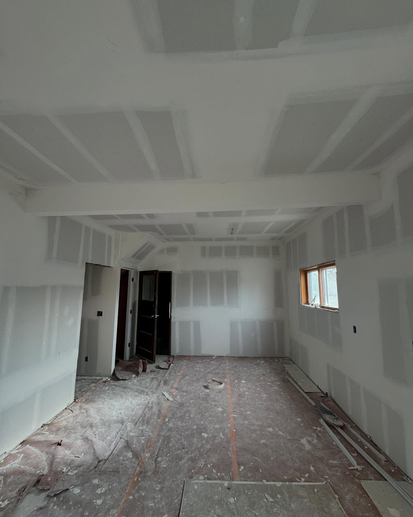 A large room with white walls and a window.