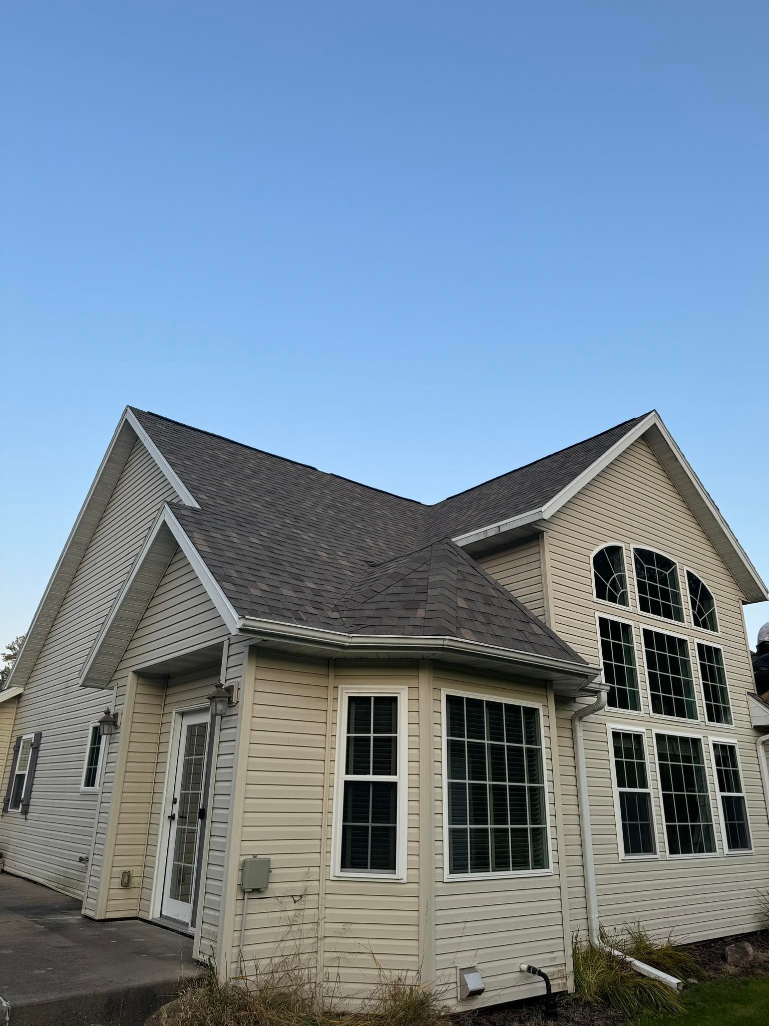 A roof of a house with a chimney and trees in the background.