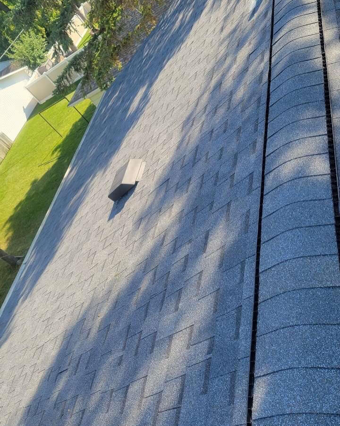 A close up of a roof with shingles and a vent on it.