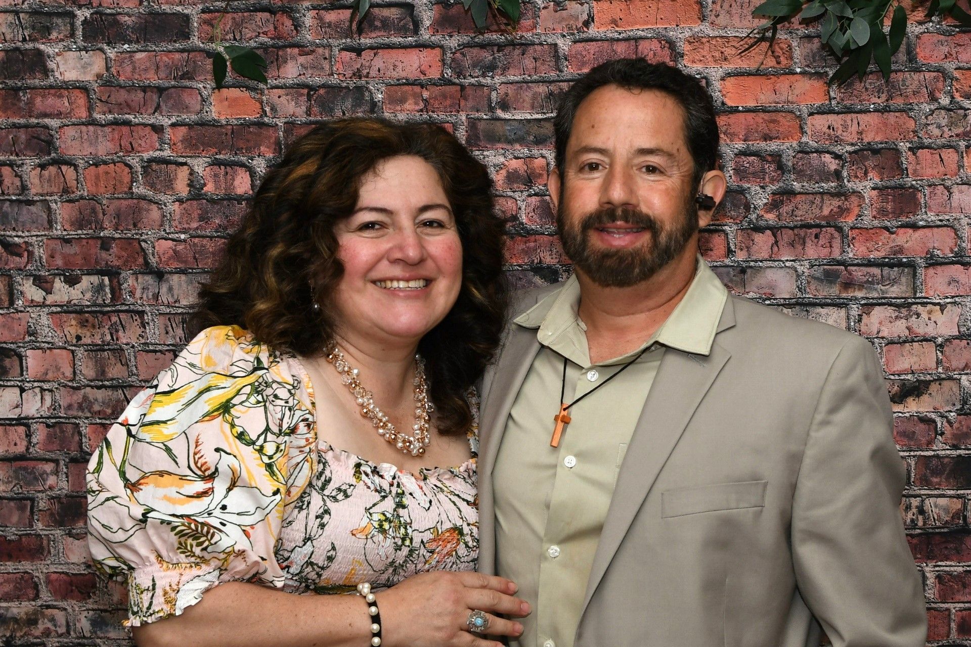 A man and a woman are posing for a picture in front of a brick wall.