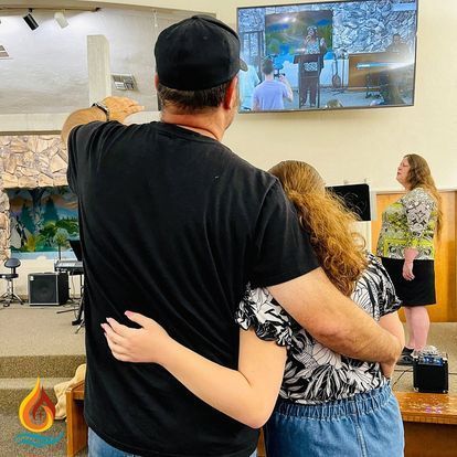 a man and a woman are hugging in front of a television in a church .