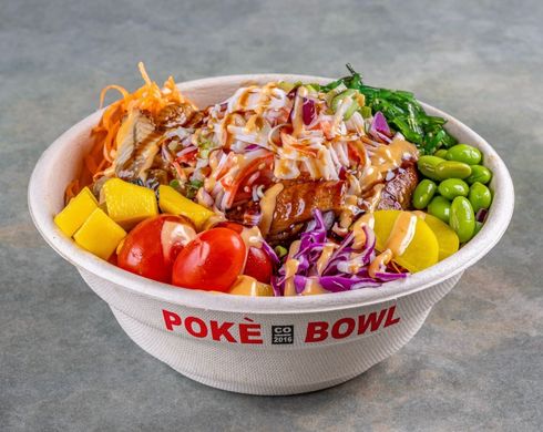 Poké bowl with avocado, mango, and greens in a restaurant-style serving counter