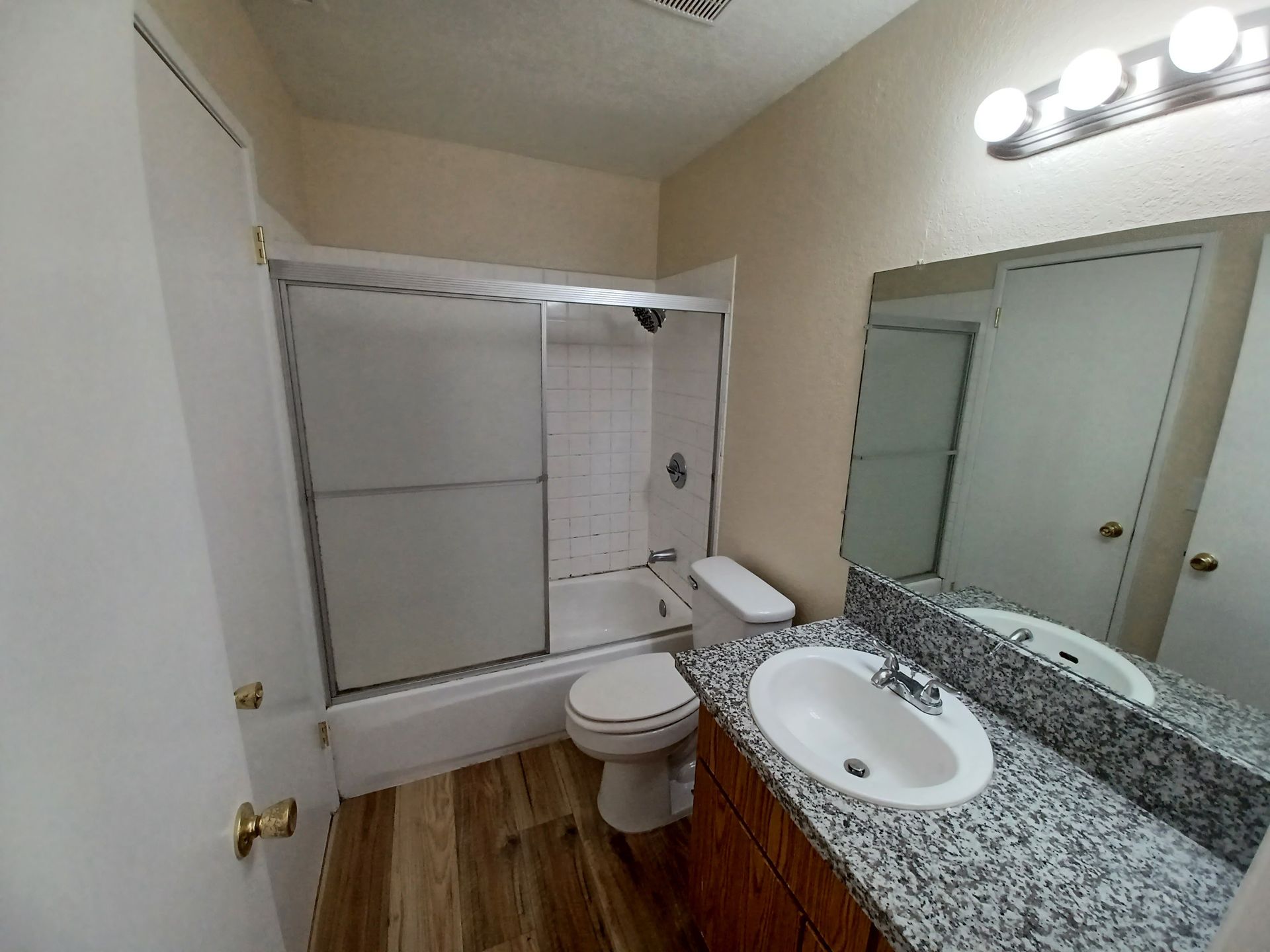 A bathroom with a toilet , sink , shower and mirror.