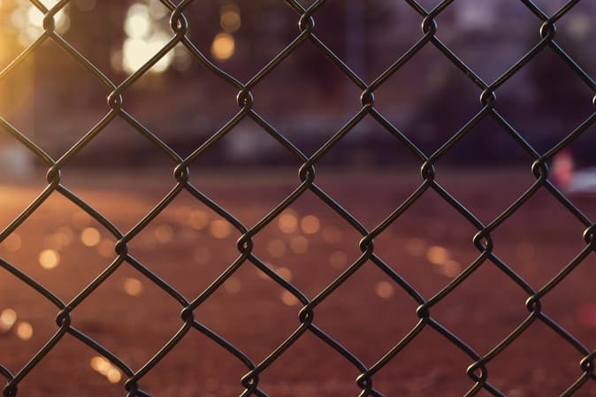 Chain-link fence with blurred city lights glowing in the background at dusk