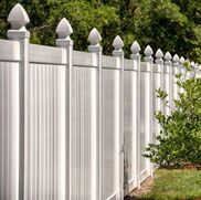 White vinyl fence with pointed finials along a green garden edge