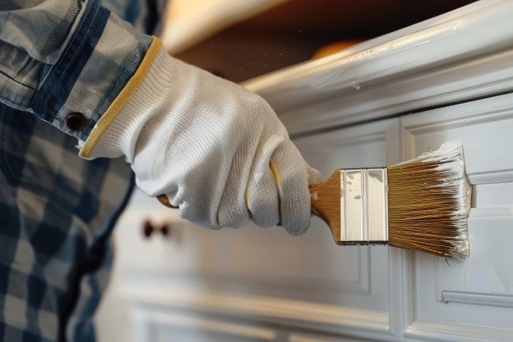A person is painting a drawer with a brush.