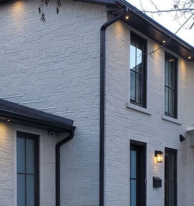 a white brick house with black windows and a black eaves trough
