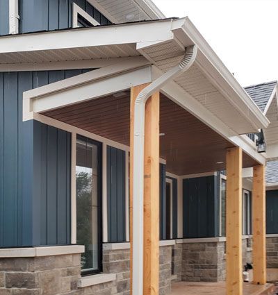 a blue house with a porch and a white eaves trough and downspouts