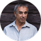 a man in a blue shirt is standing in front of a wooden wall