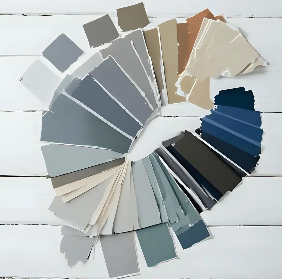 Fan of paint color swatches in gray, blue, beige, and white on a white wooden surface