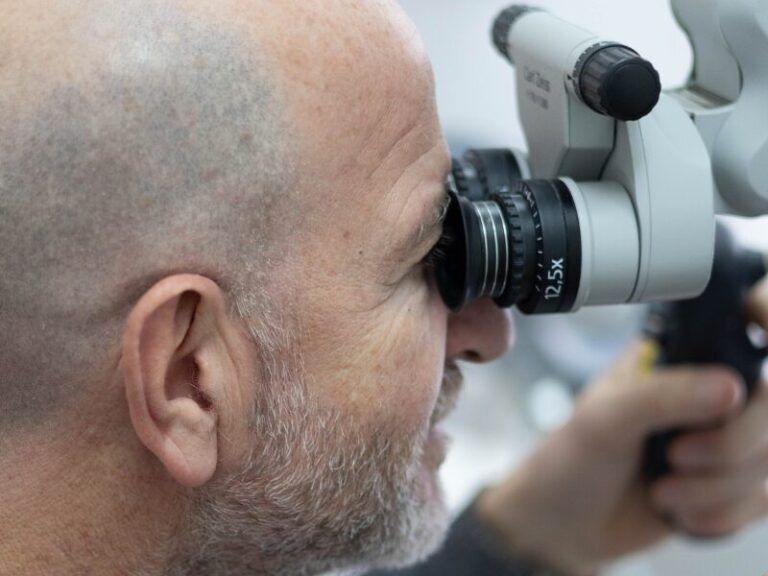 Persona che utilizza un dispositivo medico per l'esame oculistico, vista di profilo.