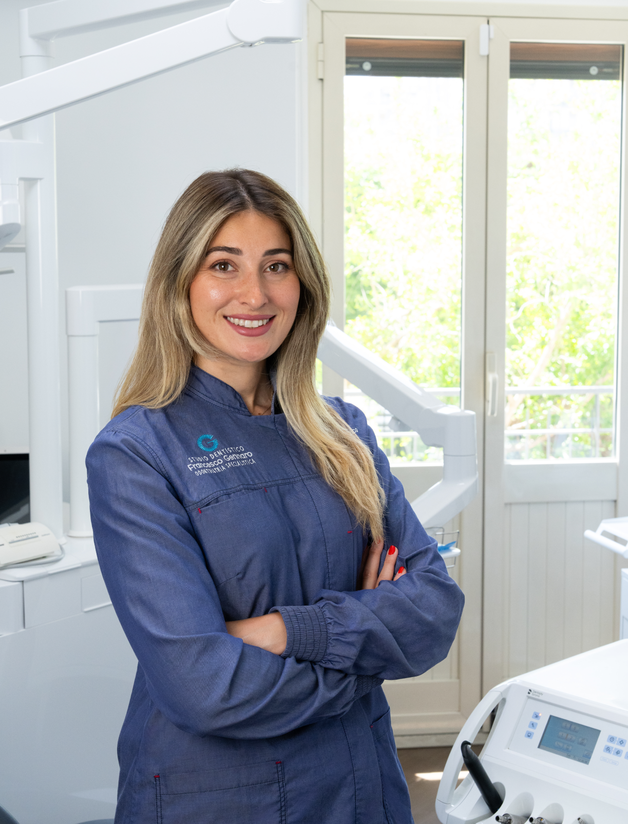 Persona sorridente in uniforme da lavoro blu in piedi davanti a un edificio.