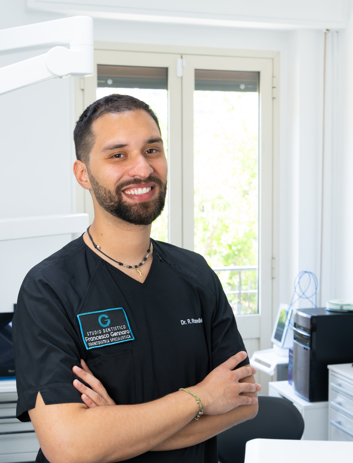 Persona sorridente in uniforme da lavoro blu in piedi davanti a un edificio.