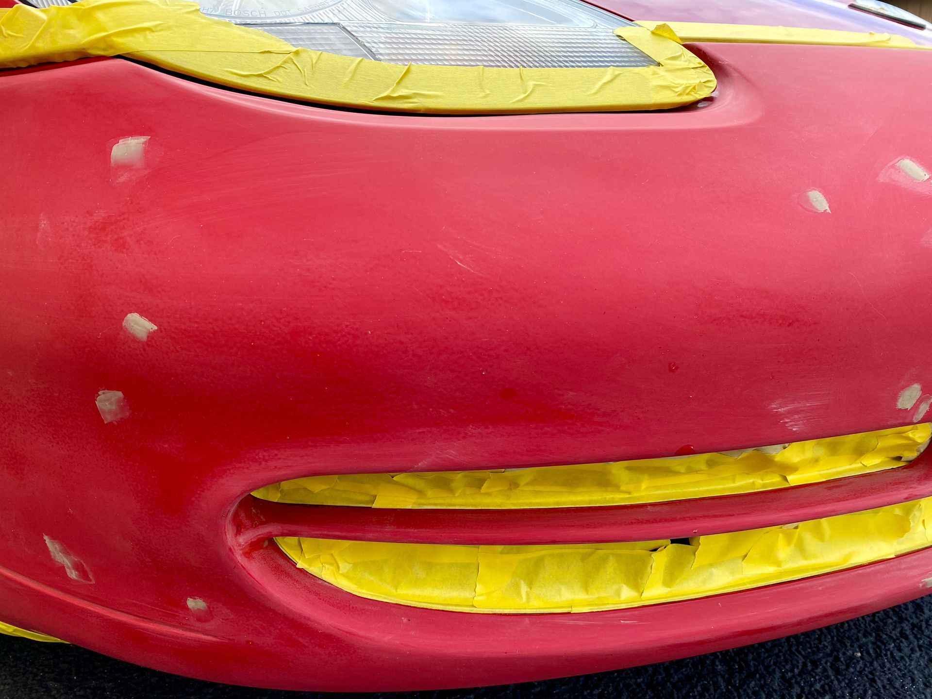 A red car with yellow tape on the front bumper