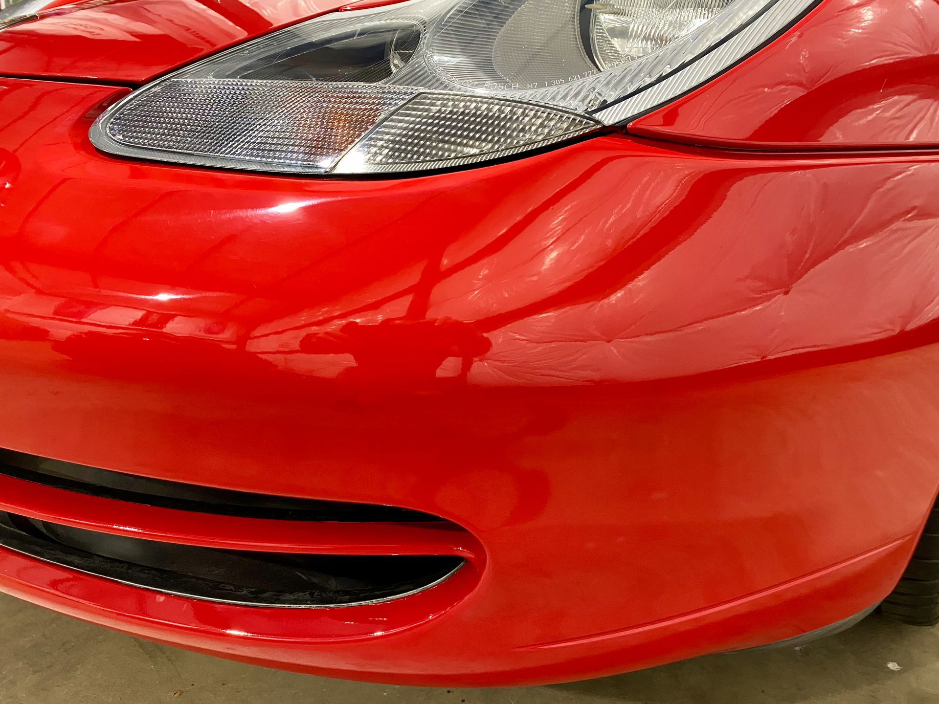 A close up of a red car 's front bumper and headlight.