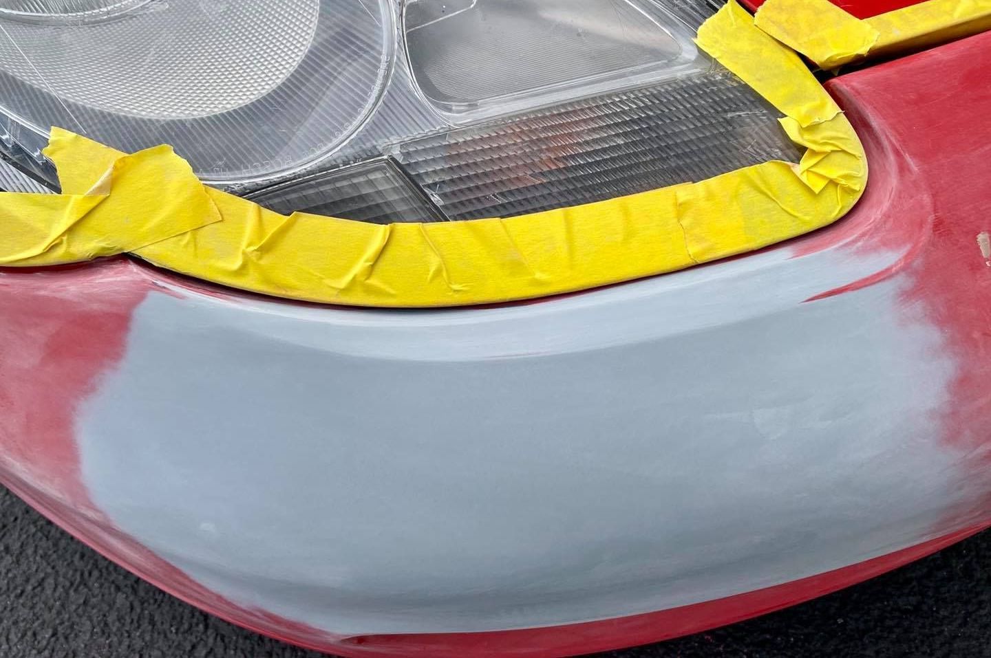 A close up of a red car with yellow tape on it.
