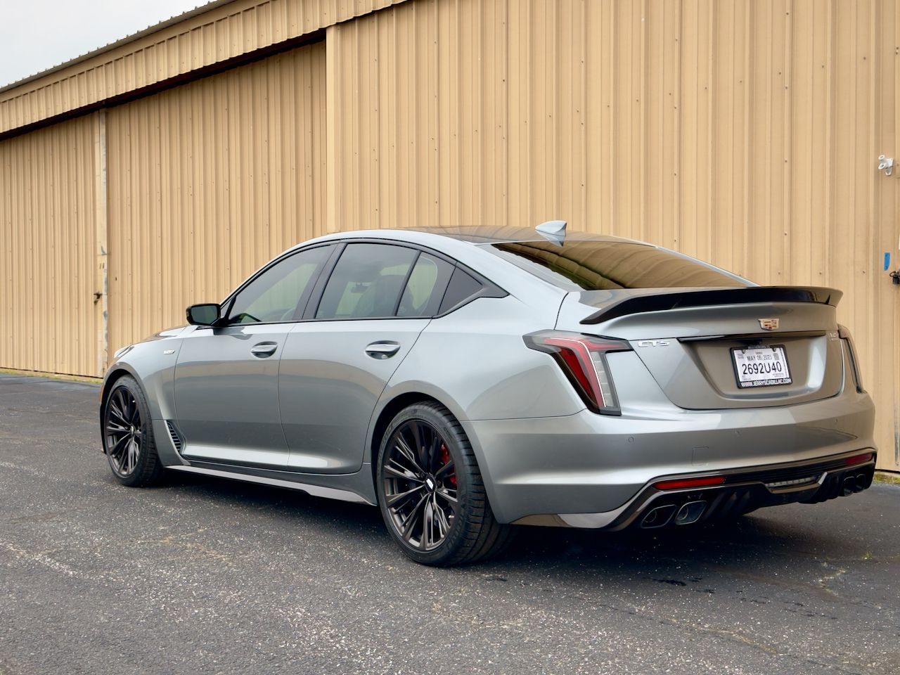Silver sedan parked beside a tan industrial building.