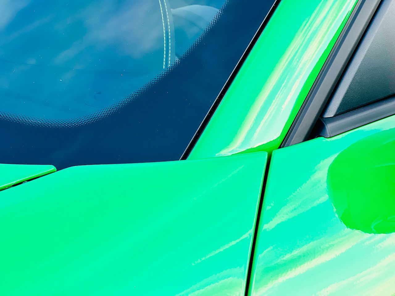 A close up of a green car with a blue sky in the background.