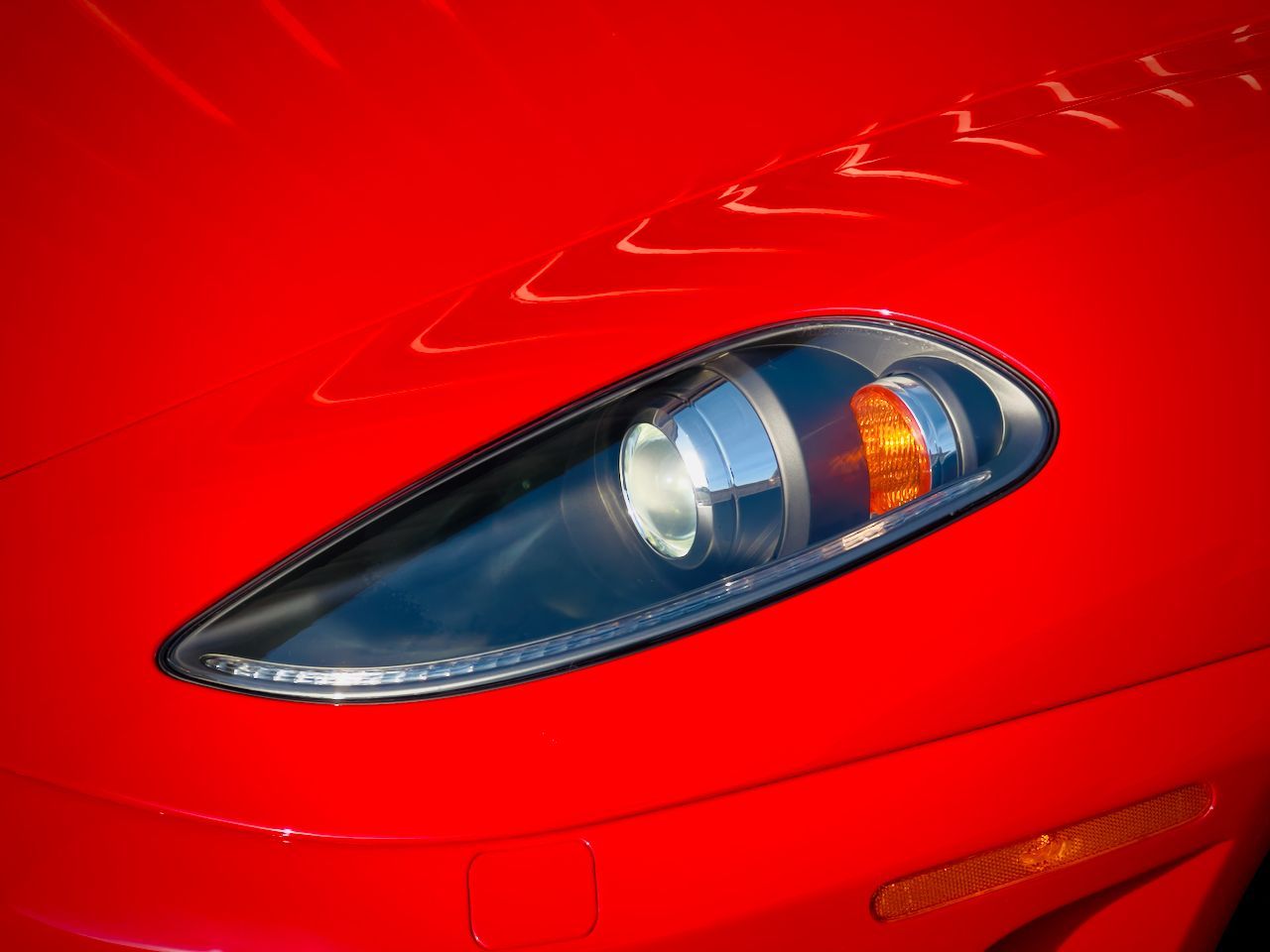 A close up of a red car 's headlight
