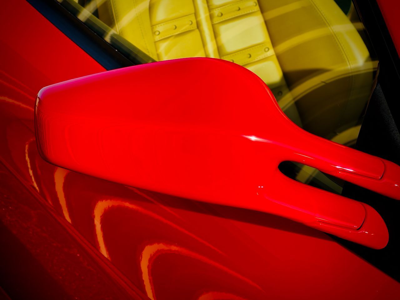 A close up of a red rear view mirror on a red car.