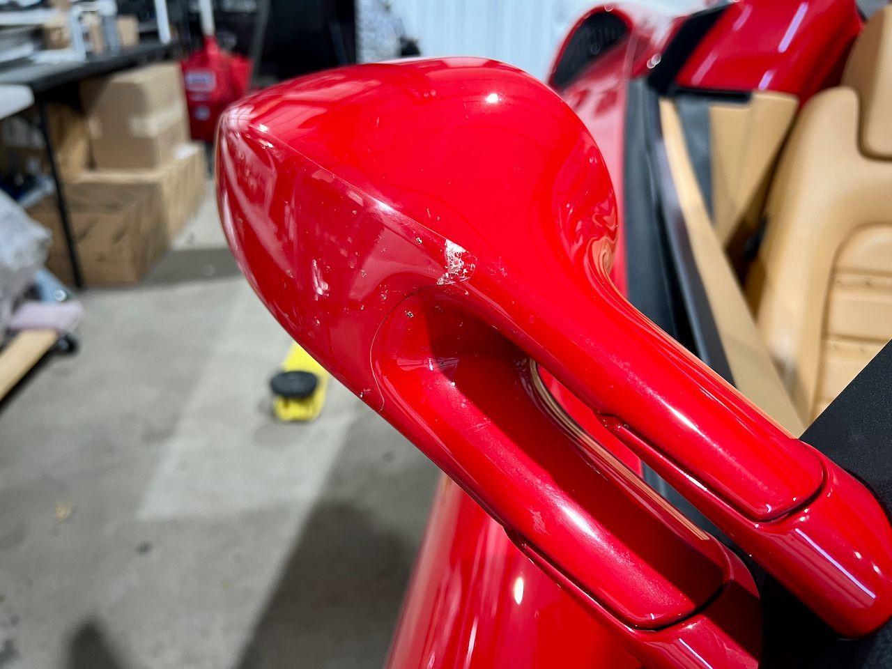 A close up of a red car 's side mirror