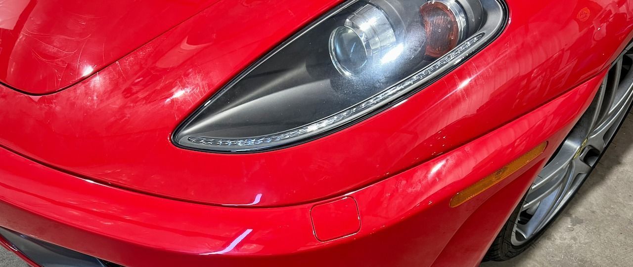 A red sports car with a black headlight is parked in a garage.