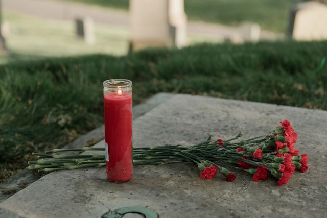 Red flowers and memorial candle at gravesite for funeral service in Arlington, TX