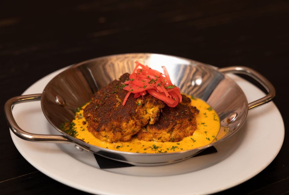 A close up of a plate of blackened crab cakes in coconut curry