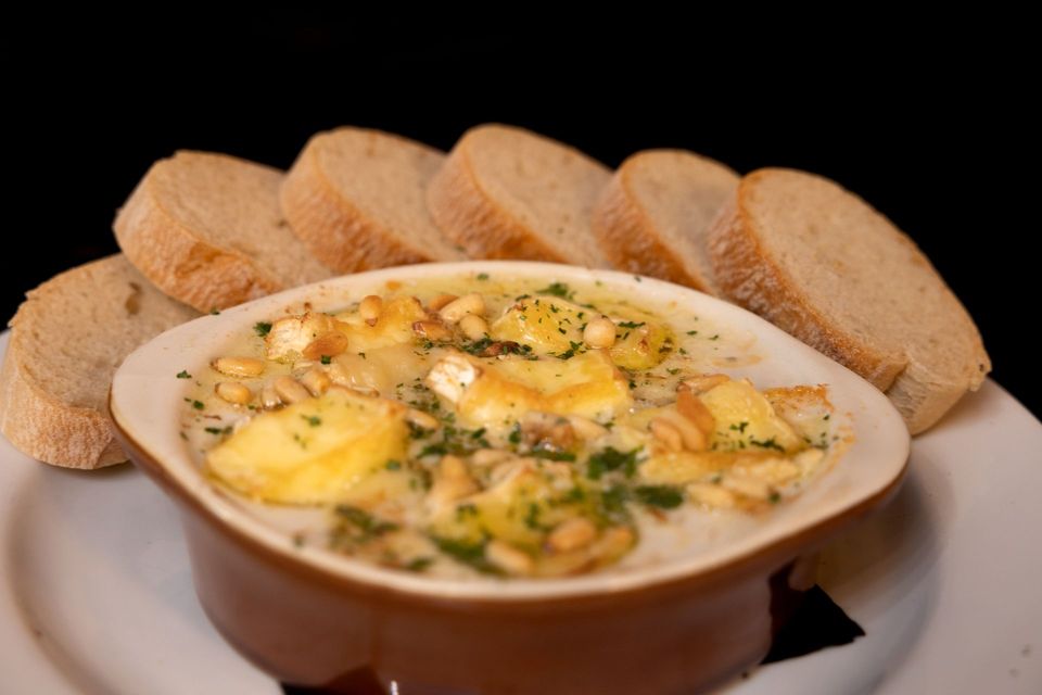 A bowl of shrimp cargot with slices of bread on a plate