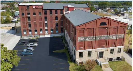 Brick industrial buildings with a parking lot. The building on the right has