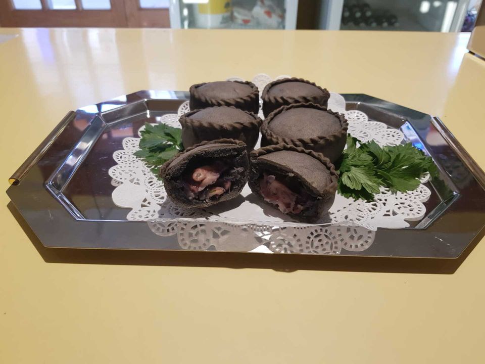 panadas con nero di seppia su piatto con prezzemolo