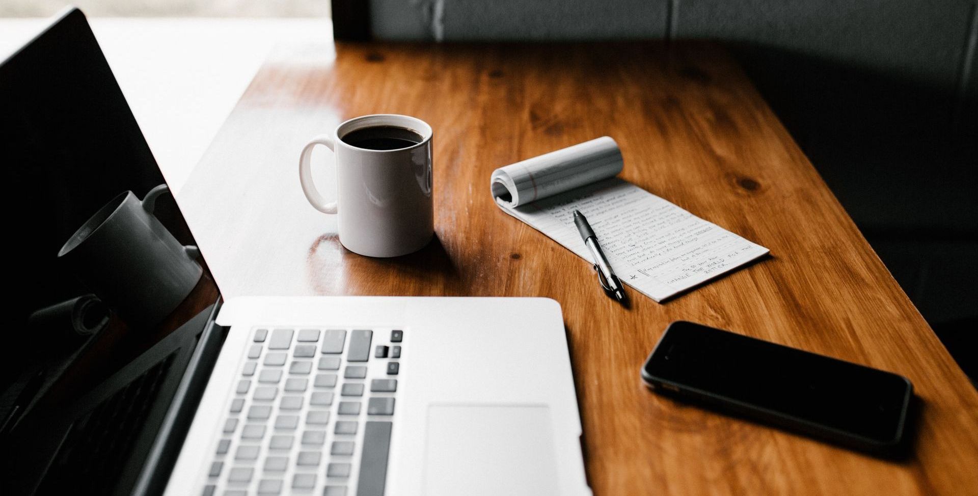 laptop, phone, coffee mug and writing pad