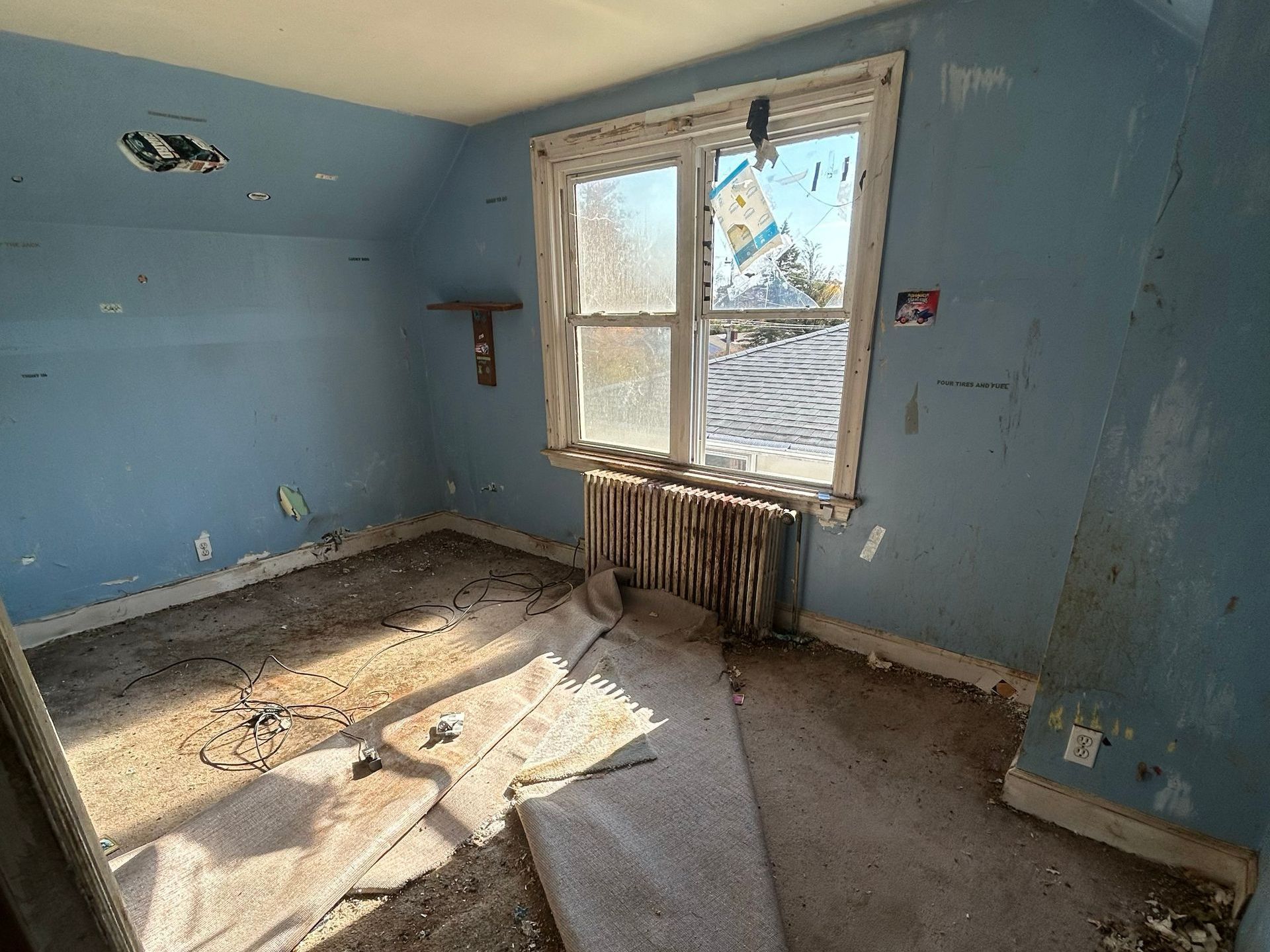 Dilapidated room with blue walls, window, and radiator. Debris covers the floor.