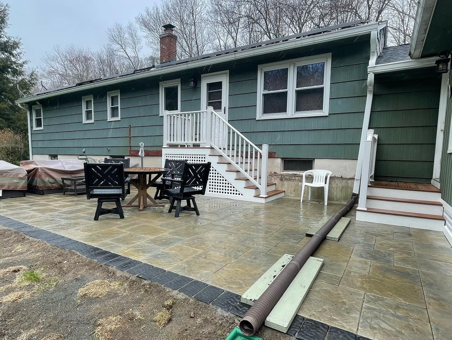 A house with a patio and a table and chairs in front of it.