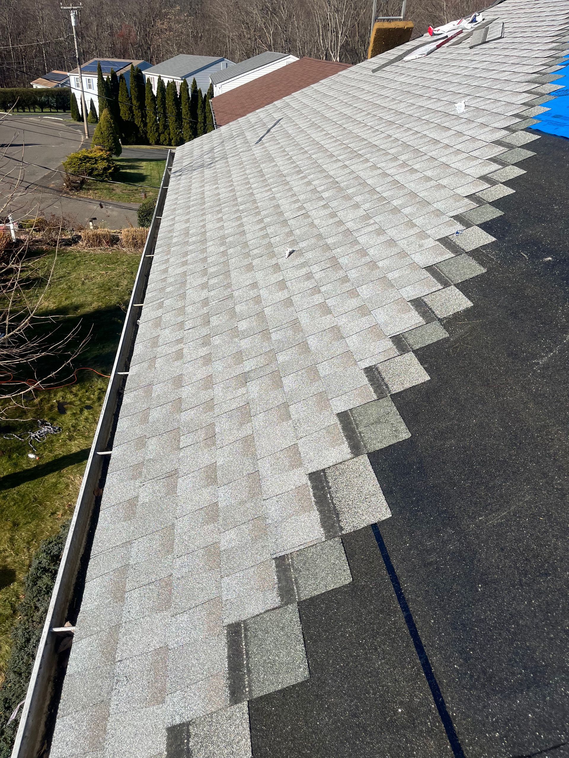 Gray asphalt shingles on a roof, angled shot with visible gutter.