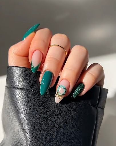 Hand with long green and nude manicured nails holding a black textured clutch.