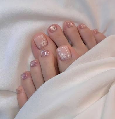 Glittery pink manicured toes resting on white satin sheets