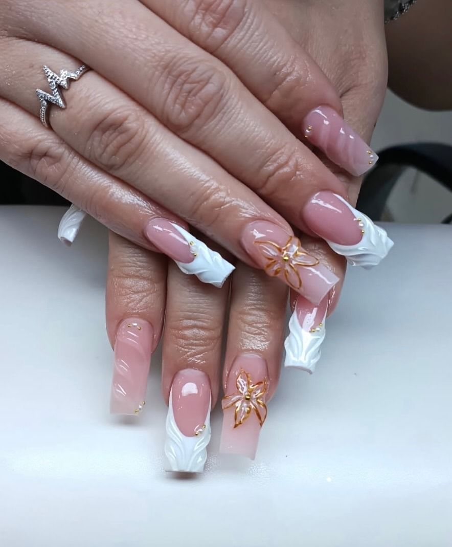 Hand with pink French tip nails and gold foil accent over a white surface, another hand resting on top