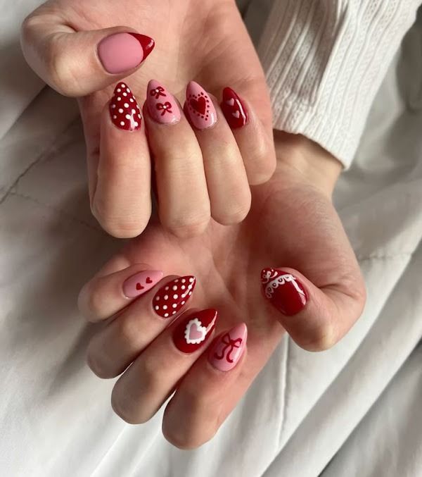 Hands showing red heart-patterned manicured nails on a light background