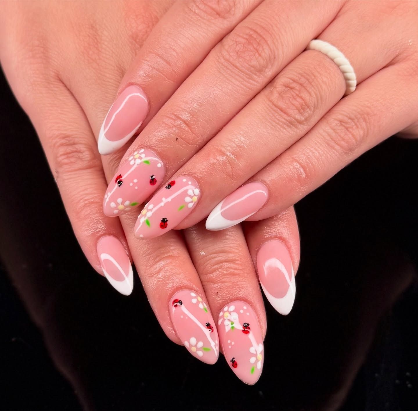 Pink floral French manicure on long almond-shaped nails, shown with hands stacked together