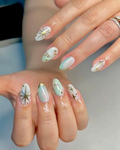 Hands with long pastel mint nails featuring delicate floral and starburst nail art.